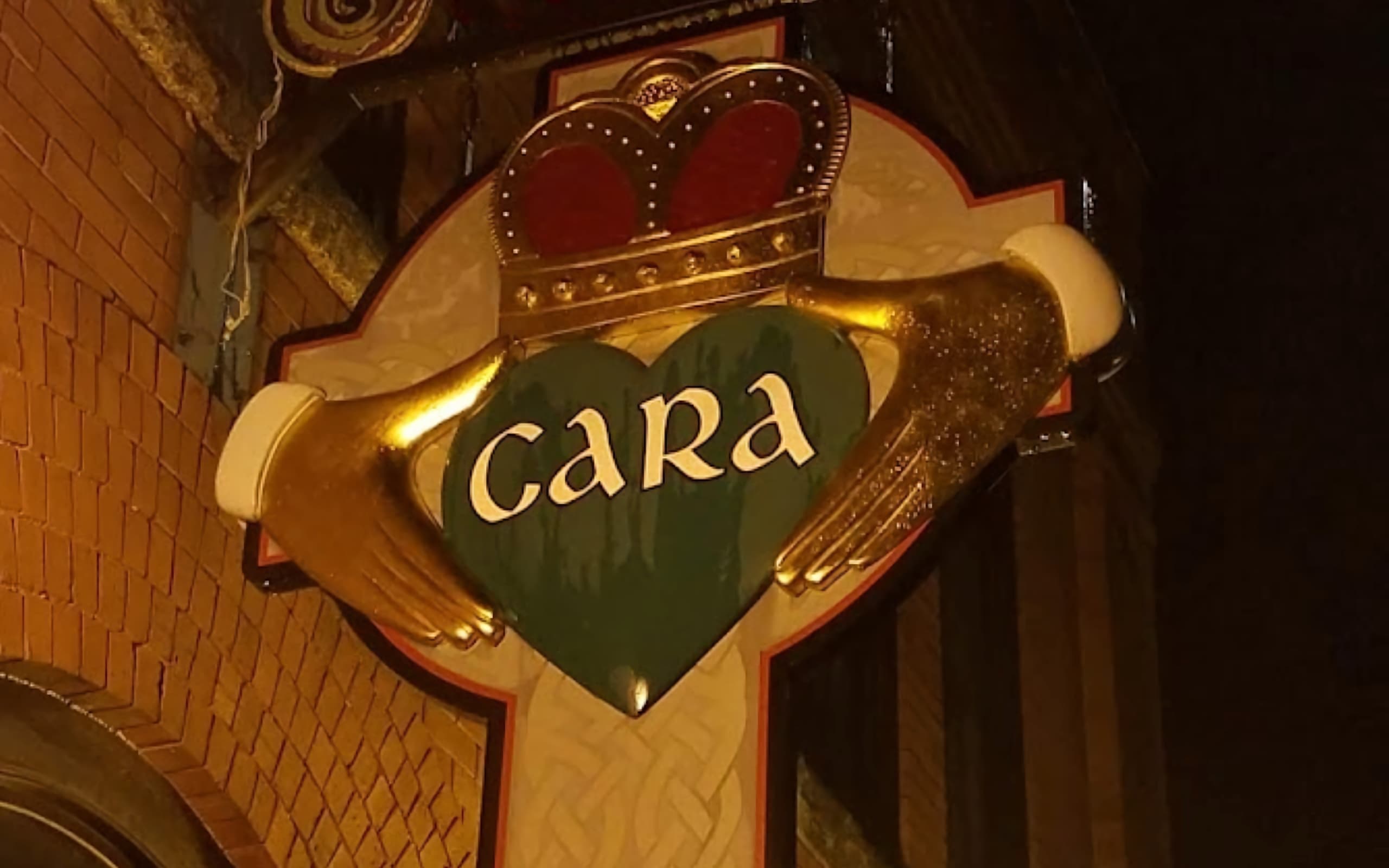 The Cara Irish Pub crest is illuminated by exterior lighting.