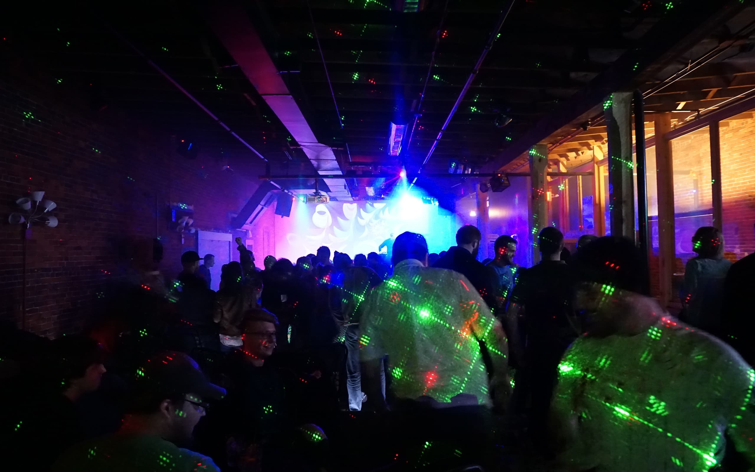 Patrons dance during an evening at Chameleon nightclub while a DJ performs on stage.