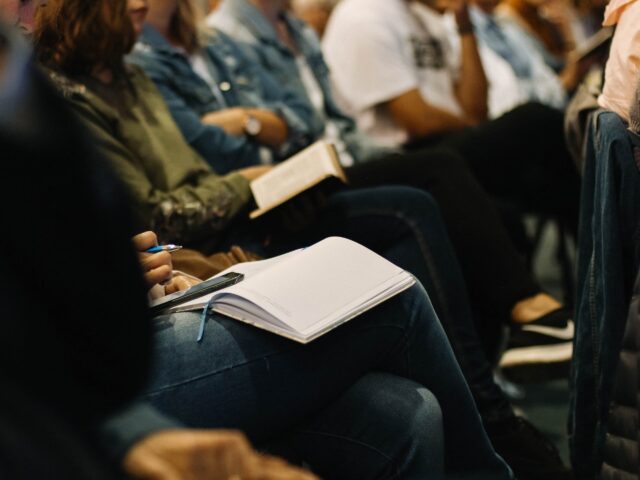 Attendees sit in the audience with notebooks during a corporate training workshop at Chameleon.