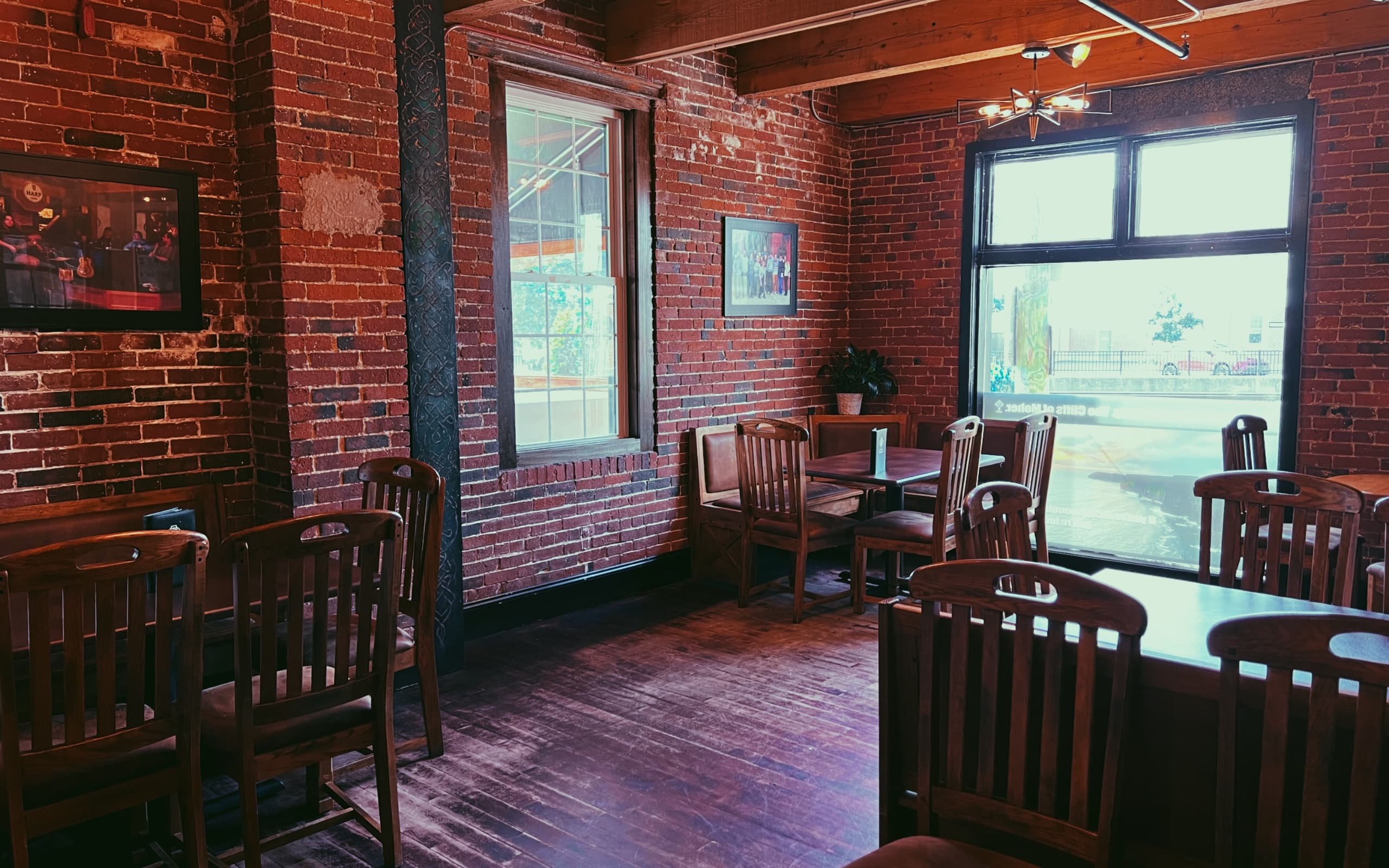 A seating area in Cara Irish Pub with exposed wood beams and historic bricks walls.
