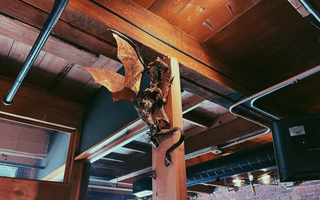 A sculpted dragon artwork crawls upward along an exposed historic beam.